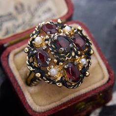 an antique ring with garnets and pearls sits in a red box on top of a table