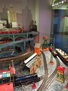 a model train set on display in a room with other toy trains and buildings around it