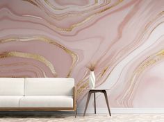 a white couch sitting in front of a wall with pink and gold paint on it