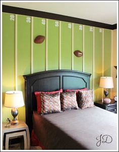 a bedroom with green walls and red pillows on the bedspread in front of a black headboard