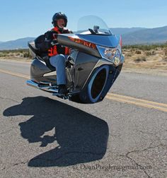 a man riding on the back of a motorcycle down a road