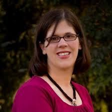 a woman wearing glasses standing in front of trees