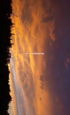 the sky is filled with clouds and some trees in front of it, as the sun sets