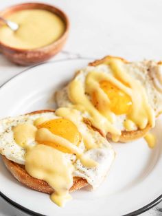 an egg on toast with hollandaise sauce on it and a bowl of mustard in the background