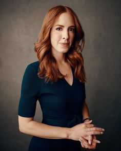 a woman in a black dress is posing for a photo with her hands folded out