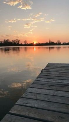 the sun is setting over water with a dock