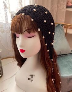 a mannequin head wearing a black hat with pearls on it's side