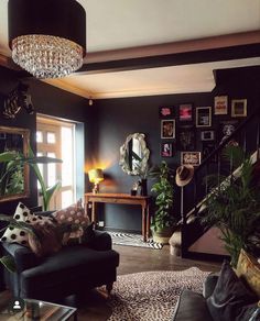 a living room filled with lots of furniture next to a stair case covered in pictures