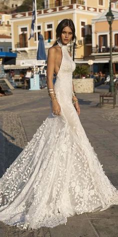 a woman in a white wedding dress standing on the street with her hand on her hip