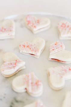 some heart shaped cookies are sitting on a plate with pink and white sprinkles