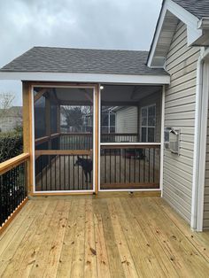 an enclosed deck with sliding glass doors and a dog on the other side looking out