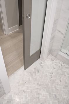 an open door leading to a bathroom with white and gray tiles on the flooring