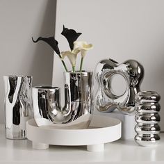 a white table topped with silver vases and flowers