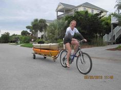 a woman riding a bike with a trailer attached to it