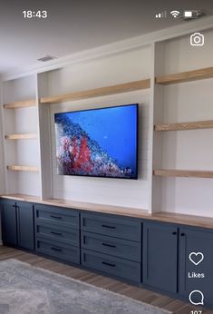 a flat screen tv mounted to the side of a wall in a living room with built - in shelving