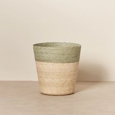 a large green and white basket sitting on top of a table next to a wall