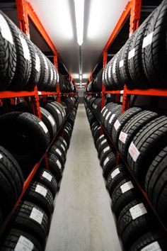 rows of tires are lined up in a storage room with orange shelves and red racks