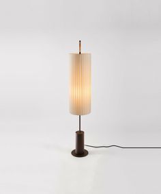 a lamp that is sitting on top of a table next to a white wall and black cord