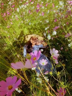 a woman is sitting in the middle of a field of wildflowers and daisies