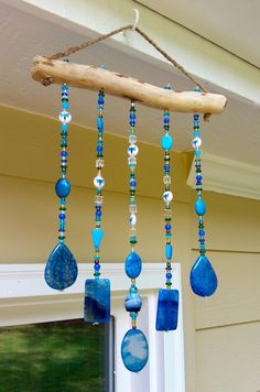 a wind chime hanging from the side of a house with blue beads and glass tears