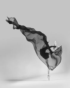 a black and white photo of a woman in a long dress flying through the air