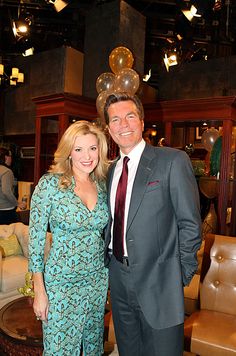 a man and woman standing next to each other in front of couches with balloons on the ceiling