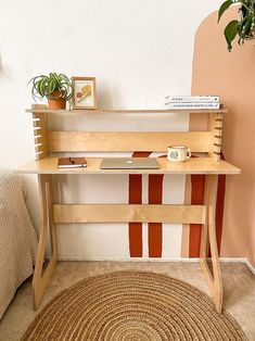 a wooden desk with a laptop on top of it next to a potted plant