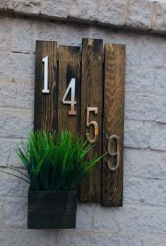 a house number sign mounted to the side of a building with grass growing in it