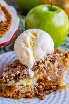 a piece of pie on a plate with ice cream and an apple in the background