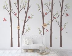 a baby's room with trees and birds painted on the wall