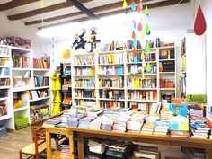 a room filled with lots of books on shelves next to a wooden table and chairs