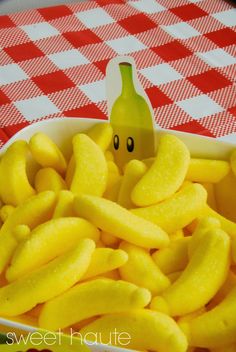 a bowl filled with yellow bananas sitting on top of a red and white checkered table cloth