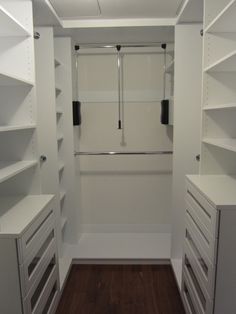 an empty walk in closet with white shelving