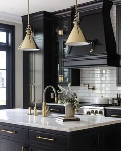 a kitchen with black cabinets and white counter tops, gold accents on the pendant lights