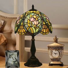 a lamp sitting on top of a wooden table next to a clock and other items