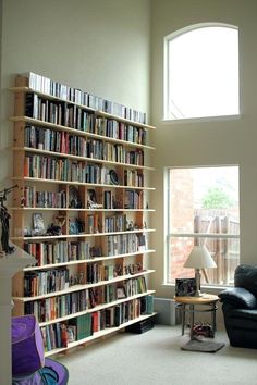 a bookshelf filled with lots of books next to a window in a room