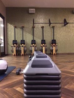 a row of exercise machines sitting on top of a hard wood floor in a gym