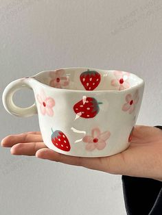 a hand holding a cup with strawberries on it