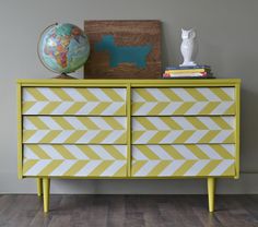 a yellow and white dresser sitting on top of a hard wood floor next to a wall