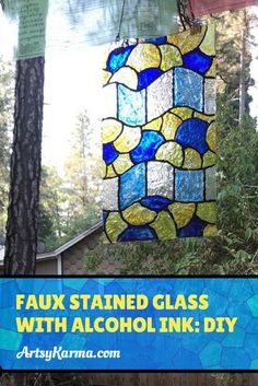 a stained glass wind chime hanging from a tree in front of a house with the words faux stained glass with alcohol ink diy