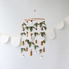 a mobile with fruit hanging from it's sides and leaves on the top of it