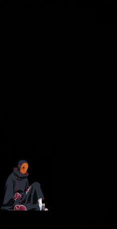 a person sitting on the ground in the dark with an orange hat and black jacket