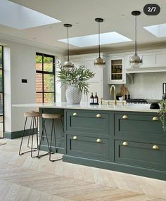 a large kitchen with an island and bar stools next to it, along with two potted plants on the counter