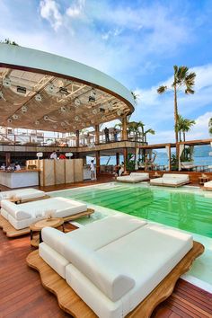 an outdoor swimming pool with lounge chairs and umbrellas on the deck overlooking the ocean