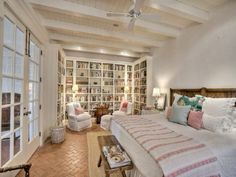 a large bed sitting inside of a bedroom next to a book shelf filled with books