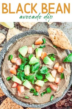 black bean avocado dip in a bowl surrounded by crackers and tortilla chips