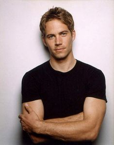 a man with his arms crossed standing in front of a white wall