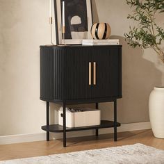 a black cabinet with gold handles and drawers in a room next to a potted plant