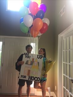 two children holding up a sign with balloons attached to it that says are you for hoco?