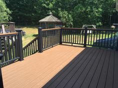 a wooden deck with black railings and a gazebo in the backgroud